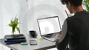 à¹oung man freelancer sitting in comfortable home office and working with computer laptop in the morning.