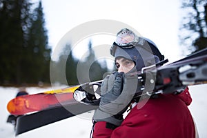 Oung man holding ski.Skier holding skis looking at the mountains.Side view of handsome skier man with mask and holding ski equipme