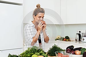 oung pretty woman with sniffing ripe tomato during cooking