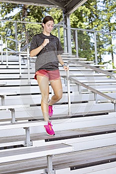 oung Woman running up and down bleacher stairs at a stadium training for her high school sports season.