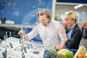 Ouple having fun while choosing fish in the supermarket.