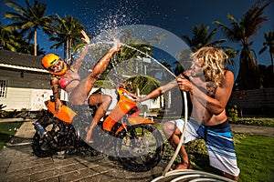 Ð¡ouple having fun with garden hose splashing summer rain