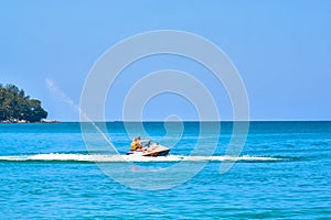 Ð¡ouple, man and woman enjoy riding ski jet in blue ocean. Island on backgraund