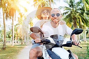 Ð¡ouple travelers riding motorbike scooter under palm trees. Traveling, vacation and transportation concept image
