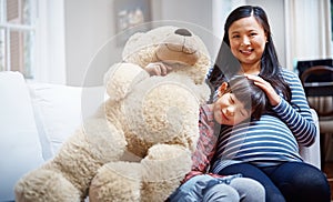 Our family is growing. Cropped portrait of a little girl sitting with her mother and her teddybear on the sofa.