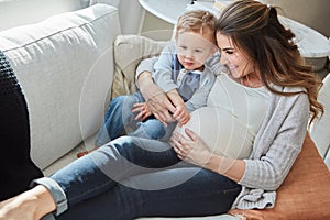 Our family is growing. a pregnant woman bonding with her toddler son at home.