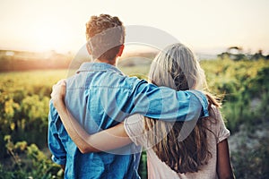 Our farm is a labour of love we live for. Rearview shot of an affectionate young couple looking over their crops on the