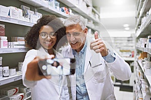 Our first work selfie together. two cheerful pharmacists posing together for a self portrait while one shows thumbs up.