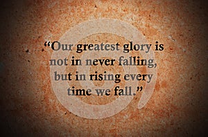 Our greatest glory is not in never falling, but in rising every time we fall. Inspirational quote on vintage retro background.