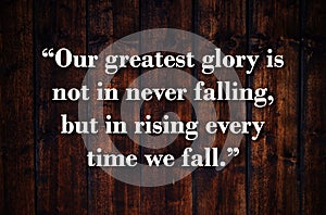 Our greatest glory is not in never falling, but in rising every time we fall. Inspirational quote on vintage retro background.