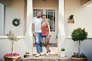 Our home is built on love. a happy young couple standing on their front porch.