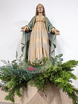 Our Lady of Grace with a bunch of green flowers and a red carnation at the base.  Church of Saint TomÃ¡s de Aquino in Lisbon