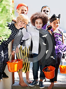 Our pales are full of candy. Portrait of a group of little children trick-or-treating on halloween.