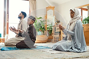 Our prayers do make a difference. a young muslim couple and their son praying in the lounge at home.