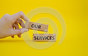 Our services symbol. Concept words Our services on wooden blocks. Beautiful yellow background. Businessman hand. Business and Our