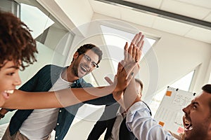 Our success Business people giving each other high-five and smiling while working together in the modern office