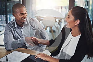 Our talents would be better merged together. two businesspeople shaking hands in an office.