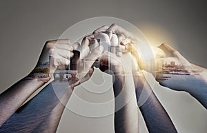 Our unity is our strength. Shot of a city superimposed over an unidentifiable business team holding hands against a gray