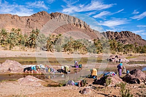 OURZAZATE, MOROCCO - JAN 2019: Berber women wash clothes in the river in beautiful picturesque place Oasis de Fint