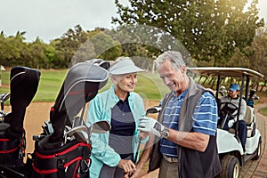 Out for a day of good green fun. a senior couple choosing their clubs while enjoying a day on the golf course.