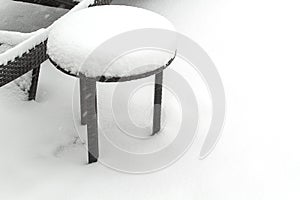 Out door patio furniture in midst of storm covered with snow