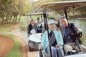 Out for a drive. a smiling senior couple riding in a cart on a golf course.