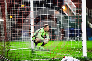 Out of focus goalkeeper crouching down near the goal post