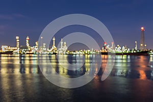 Out of focus, Oil refinery at twilight with river reflection