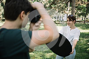 Out of focus photographer taking photos of woman in park