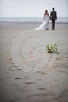 Out of focus and unrecognizable bride and groom walking away on the beach
