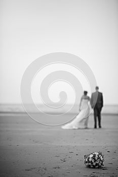 Out of focus and unrecognizable bride and groom walking away on the beach