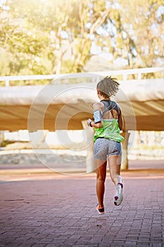 Out on her daily jog. Rear view shot of a sporty young woman out for a run.
