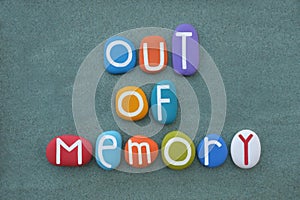 Out of memory, text composed with multi colored stone letters over green sand