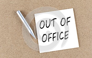 OUT OF OFFICE text on sticky note on a cork board with pencil