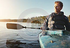 Out on the water where he longed to be. a young man kayaking on a lake outdoors.