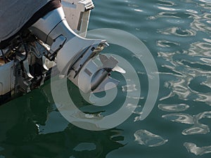 Outboard motor with propellor out of water, on the back of a small boat