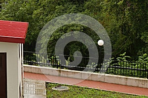 Outbuilding in a well-groomed city courtyard against the background of vegetation during the rain