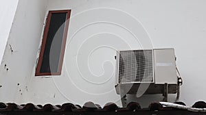 outdoor ac unit mounted on a white wall on the top floor of a house