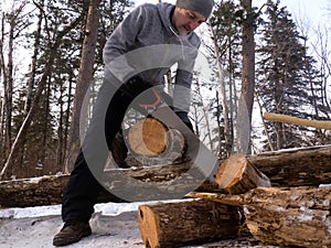 Outdoor activities: a man saws wood in a forest for a fire. Arrangement of a tent camp