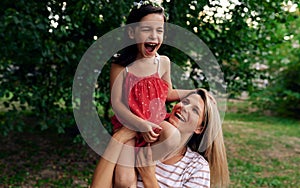 Outdoor activities of a mother playing with her daughter in the park. Happy woman hugging and having fun with her child enjoying