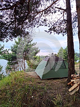Outdoor activities, vacations: camping with a tent on the cliff of the lake shore