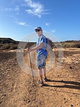 Outdoor activity in nature concept. Carefree sporty senior man walking in arid landscape in Tenerife enjoying healthy lifestyle