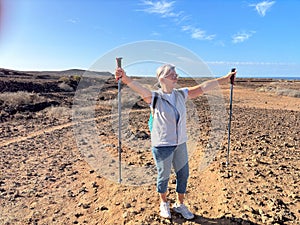 Outdoor activity in nature concept. Carefree sporty senior woman walking in arid landscape in Tenerife enjoying healthy lifestyle