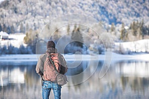 Outdoor adventure: Caucasian man is standing at the lakeshore and enjoys the view. Beautiful winter landscape, Austria