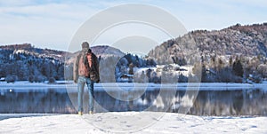 Outdoor adventure: Caucasian man is standing at the lakeshore and enjoys the view. Beautiful winter landscape, Austria