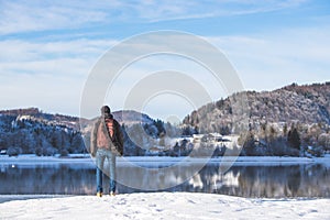 Outdoor adventure: Caucasian man is standing at the lakeshore and enjoys the view. Beautiful winter landscape, Austria