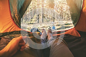 Outdoor adventure tourism - man laying in tent with cup of tea