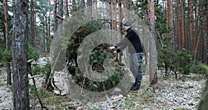 Outdoor adventures in winter - man building tree branch camp into the wild