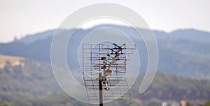 Outdoor aerial television antenna on the roof of a house in a rural town surrounded by mountains