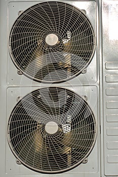 An outdoor air conditioner unit consisting of two fans. A large industrial air conditioner on the wall of a store or enterprise.